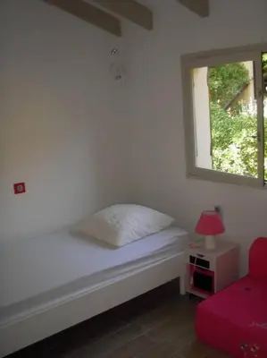 a white bed with a window and a red chair at Maison golfe d'Ajaccio: vue mer in Pietrosella