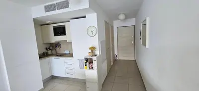 a kitchen with white cabinets and a clock on the wall at T2 de Standing Coté Plage, les pieds dans l'eau in Propriano