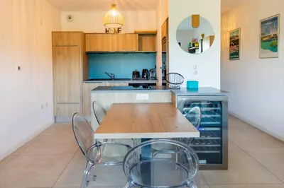 a kitchen with a wooden table and chairs at La Clé Terrasse, Proche port,centre, parking,clim in Porto-Vecchio