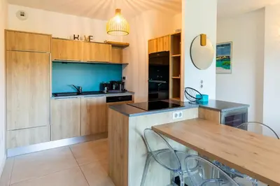 a kitchen with wooden cabinets and a table with chairs at La Clé Terrasse, Proche port,centre, parking,clim in Porto-Vecchio