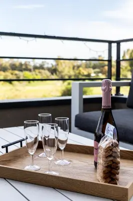 a bottle of wine and four wine glasses on a tray at La Clé Terrasse, Proche port,centre, parking,clim in Porto-Vecchio