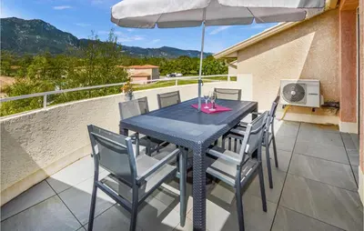 a table with chairs and an umbrella on a patio at Lovely Apartment In Sta Maria Poggio in Moriani Plage