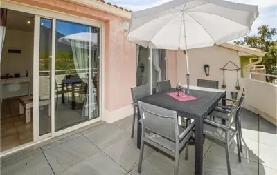a patio table with an umbrella on a balcony at Lovely Apartment In Sta Maria Poggio in Moriani Plage