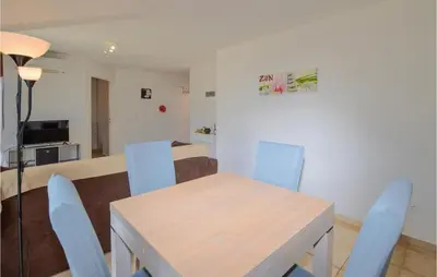 a dining room with a table and blue chairs at Lovely Apartment In Sta Maria Poggio in Moriani Plage