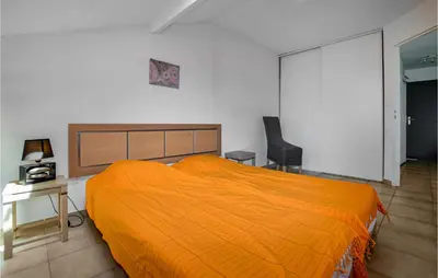 a bedroom with a large orange bed and a chair at Lovely Apartment In Sta Maria Poggio in Moriani Plage