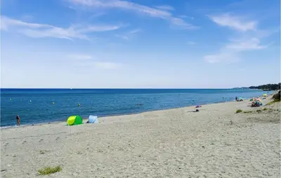 a beach with a group of people and the ocean at Lovely Apartment In Sta Maria Poggio in Moriani Plage