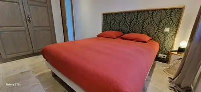 a bedroom with a large red bed with two red pillows at A Pasturella, Jacuzzi Spa in Venzolasca