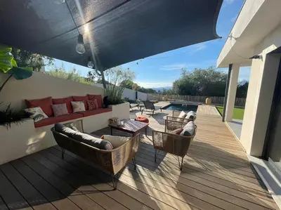 a patio with a couch and chairs and an umbrella at Maison villa 3 chambres plage Agosta proche Porticcio in Pietrosella