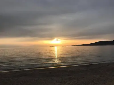 a sunset on the beach with the sun setting at Maison villa 3 chambres plage Agosta proche Porticcio in Pietrosella