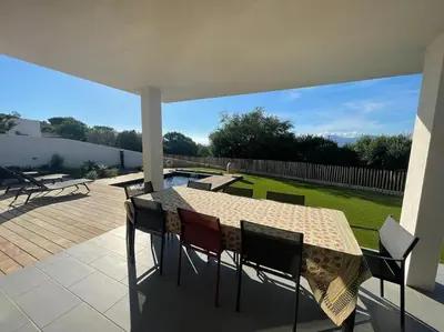 a patio with a table and chairs and a pool at Maison villa 3 chambres plage Agosta proche Porticcio in Pietrosella