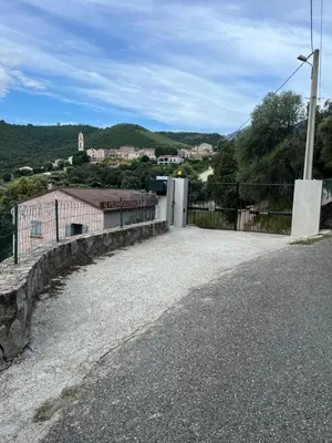 a driveway with a fence and a building on a hill at Charmant T2 proche de Corte in Soveria