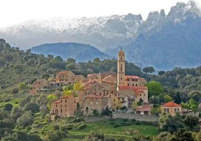 a large building on a hill with mountains in the background at Charmant T2 proche de Corte in Soveria