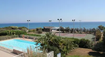 a pool and tennis court with the ocean in the background at Prunete - Appartement - 2 personnes - Piscine in Cervione