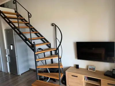 a spiral staircase in a living room next to a tv at Prunete - Appartement - 2 personnes - Piscine in Cervione