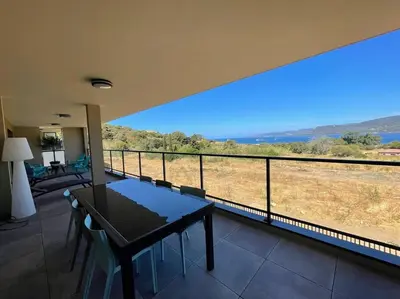 a house with a balcony with a table and chairs at Spacieux appart- 6PERS- VUE MER- 2 min de la plage in Propriano