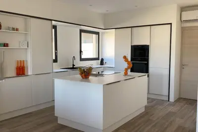 a kitchen with white cabinets and a white counter top at Spacieux appart- 6PERS- VUE MER- 2 min de la plage in Propriano