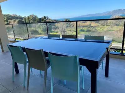 a dining table and chairs on a balcony with a view at Spacieux appart- 6PERS- VUE MER- 2 min de la plage in Propriano