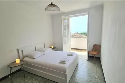 a white bedroom with a bed and a window at Spacious apartment with sea view in Ajaccio
