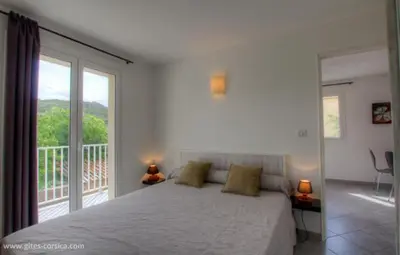 a bedroom with a large bed and a balcony at Village Cargese 1 in Cargèse