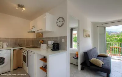 a kitchen with a counter and a clock on the wall at Village Cargese 1 in Cargèse