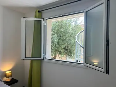 a window in a room with a green curtain at Village Cargèse 2 in Cargèse