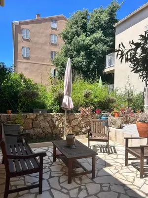 a patio with chairs and a table and an umbrella at Idéal emplacement Cargese 3 in Cargèse