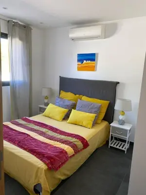 a bedroom with a bed with yellow and blue pillows at Charmant T3 5 min de porticcio in Porticcio