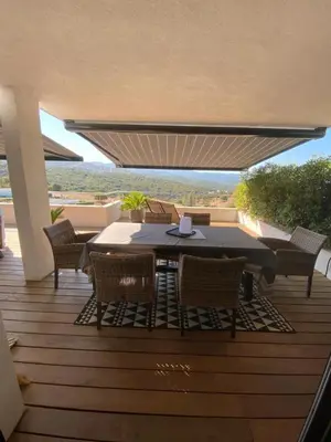 a patio with a table and chairs on a deck at Charmant T3 5 min de porticcio in Porticcio