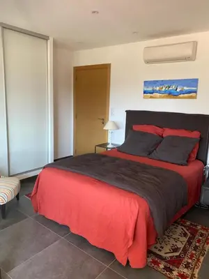 a bedroom with a large bed with a red blanket at Charmant T3 5 min de porticcio in Porticcio