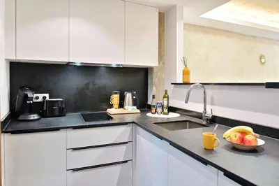 a kitchen with white cabinets and a bowl of fruit on the counter at Résidence Mademoiselle Joséphine in Ajaccio