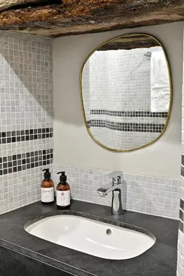 a bathroom sink with a round mirror above it at Résidence Mademoiselle Joséphine in Ajaccio