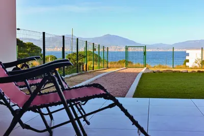 a chair sitting on a porch overlooking the water at T3 vue mer 100 m2 de jardin 'D' in Pietrosella