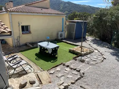 a small backyard with a table and grass at Proche Ajaccio maisonnette indépendante 4 personnes au calme in Alata