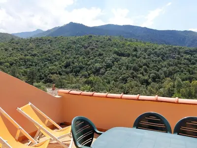 a balcony with chairs and a table and mountains at Apartment Residence Cabanaccia 3 Pieces 6 Pers-2 by Interhome in Serriera