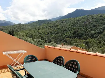 a table and chairs on a balcony with a view of mountains at Apartment Residence Cabanaccia 3 Pieces 6 Pers-3 by Interhome in Serriera