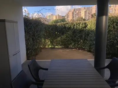 a table on a porch with a view of a garden at T2 standing Ajaccio in Ajaccio