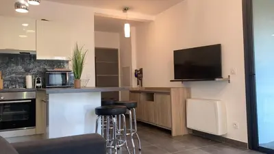 a kitchen with a bar with stools and a tv at T2 standing Ajaccio in Ajaccio