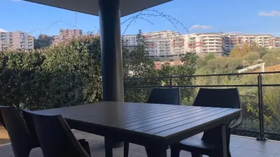a wooden table and chairs on a balcony with buildings at T2 standing Ajaccio in Ajaccio