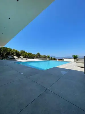a large swimming pool with the ocean in the background at Villa luxe avec piscine et belle vue mer in Pietrosella