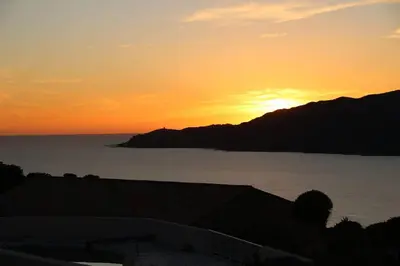a sunset over a body of water with a mountain at CHEZ ADRIEN 108-Appartement magnifique vue mer piscine chauffée in Serra-di-Ferro