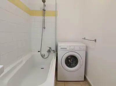 a bathroom with a washing machine next to a bath tub at CHEZ ADRIEN 108-Appartement magnifique vue mer piscine chauffée in Serra-di-Ferro