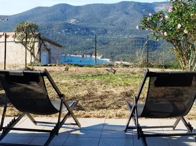 two chairs sitting on a porch with a view of a mountain at CHEZ ADRIEN 108-Appartement magnifique vue mer piscine chauffée in Serra-di-Ferro