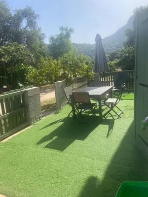a table and chairs with an umbrella on a lawn at Appartement proche du départ du GR20 in Calenzana