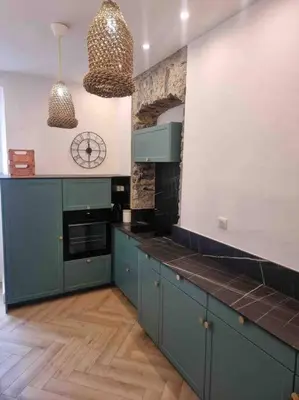 a kitchen with blue cabinets and a clock on the wall at Appartement au cœur de la ville in Corte