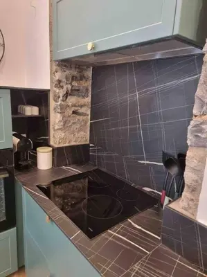 a kitchen with a black counter top and black tiles at Appartement au cœur de la ville in Corte