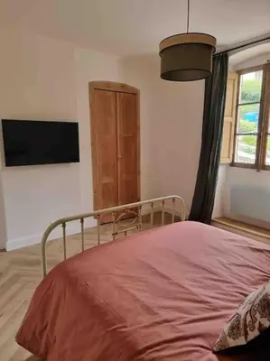 a bedroom with a bed and a flat screen tv at Appartement au cœur de la ville in Corte