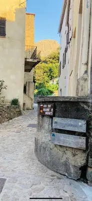 a sign on a stone wall next to a building at Calenzana GR20 in Calenzana