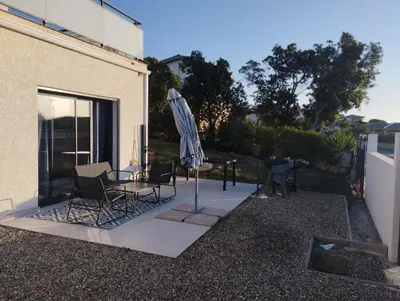 a patio with a table and an umbrella and chairs at Beau logement neuf à 5 mn de la mer in Ventiseri