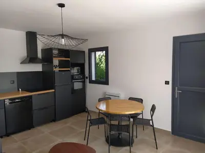 a kitchen with a table and chairs in a room at Beau logement neuf à 5 mn de la mer in Ventiseri
