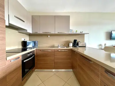 a kitchen with wooden cabinets and a sink and a microwave at Appartement Résidence Salin Bay in Porto-Vecchio